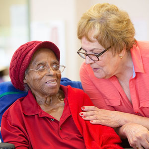 Hispanic and  African American women together in a busy senior center